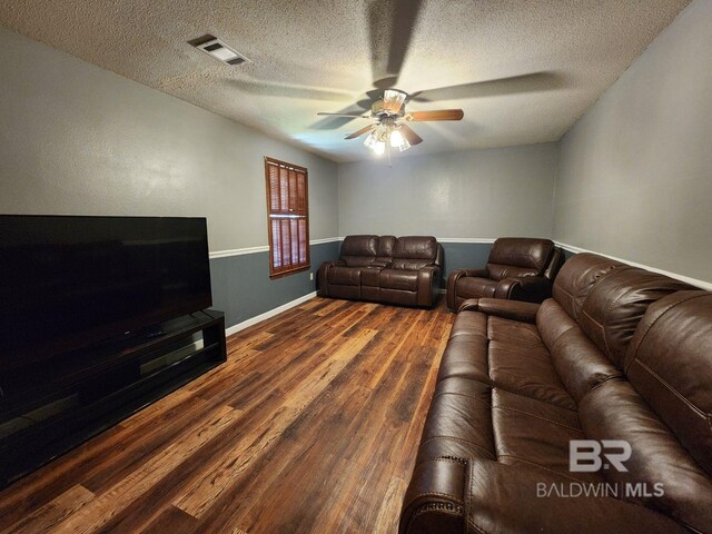 living room featuring dark hardwood / wood-style floors, ceiling fan, and a textured ceiling