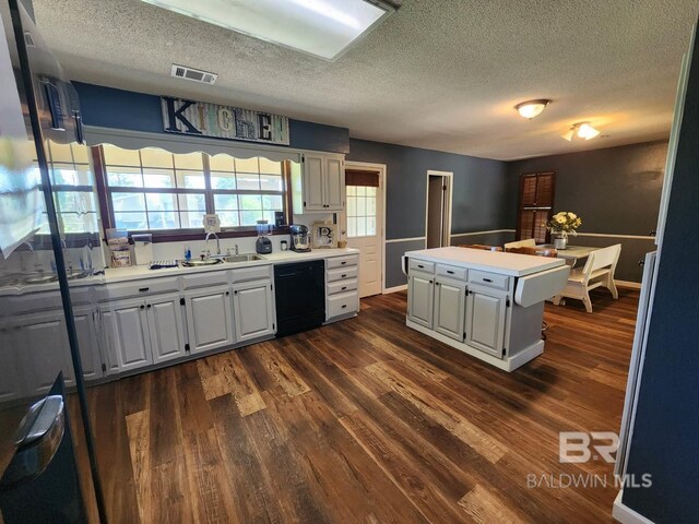 kitchen with black dishwasher, dark hardwood / wood-style floors, white cabinets, and a textured ceiling