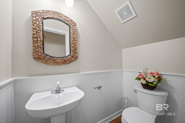 7750 Charleston Oaks Dr, Daphne, AL 36526 - half bath with wainscoting, a sink, toilet, lofted ceiling, and visible vents