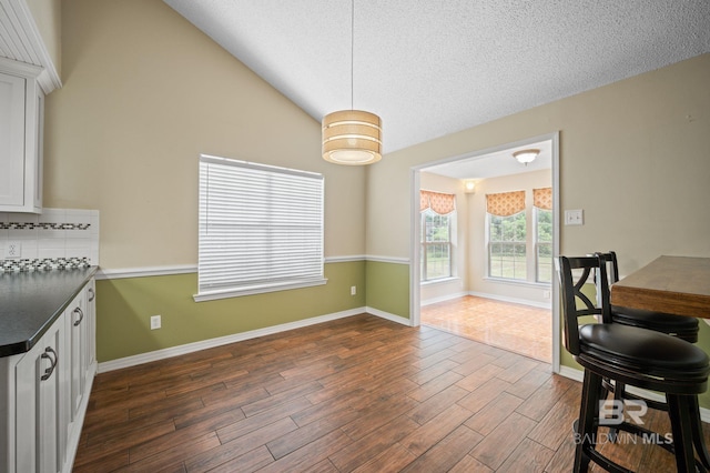 7750 Charleston Oaks Dr, Daphne, AL 36526 - dining room with baseboards, vaulted ceiling, dark wood-style flooring, and a textured ceiling