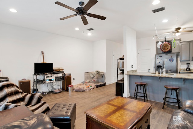 living room featuring light hardwood / wood-style floors, ceiling fan, and sink