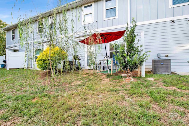 rear view of property with a lawn and central air condition unit