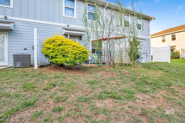 back of property featuring central air condition unit and a yard