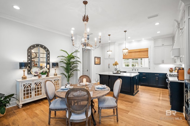 dining room featuring a notable chandelier, crown molding, light wood-type flooring, and sink