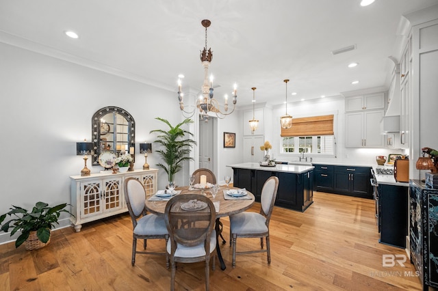 dining room featuring crown molding, sink, a notable chandelier, and light wood-type flooring