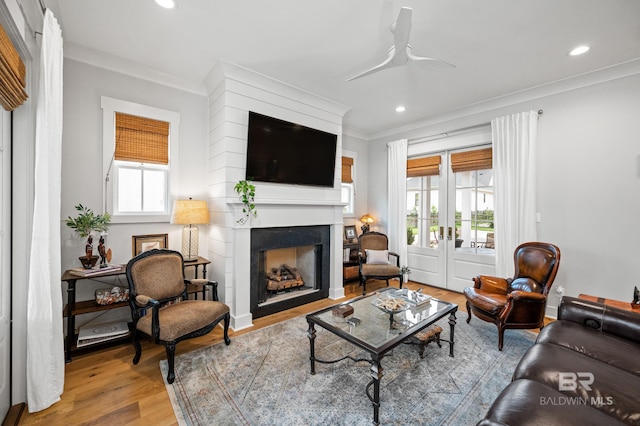 living room featuring ceiling fan, wood-type flooring, and ornamental molding