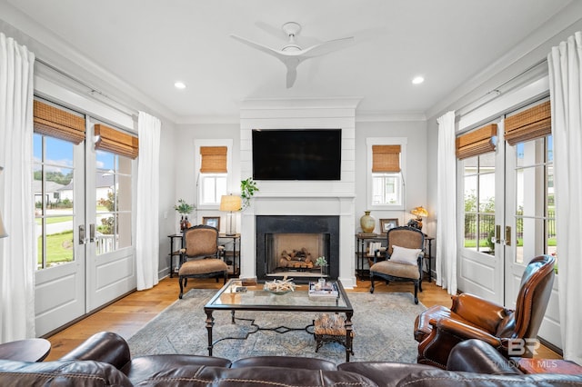 living room featuring crown molding, french doors, ceiling fan, and light wood-type flooring