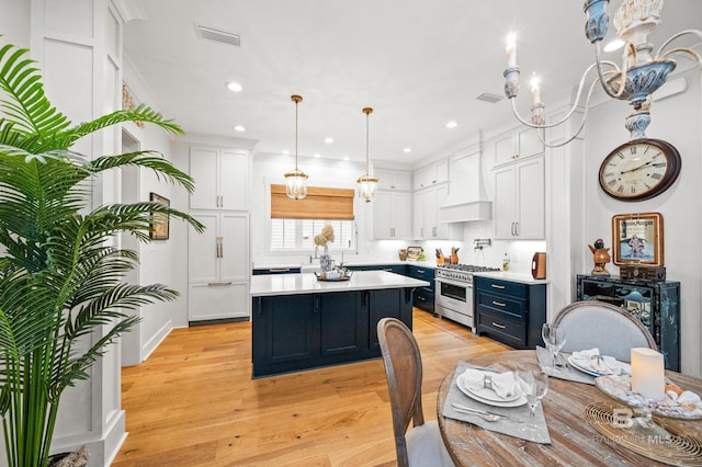 kitchen with custom exhaust hood, a kitchen island, white cabinetry, and high end stainless steel range