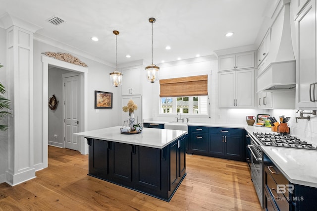 kitchen with white cabinets, light wood-type flooring, a center island, and premium range hood