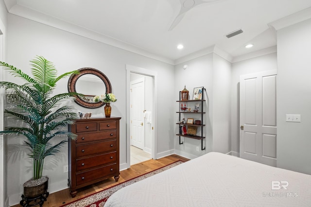 bedroom with ceiling fan, ornamental molding, connected bathroom, and light hardwood / wood-style flooring