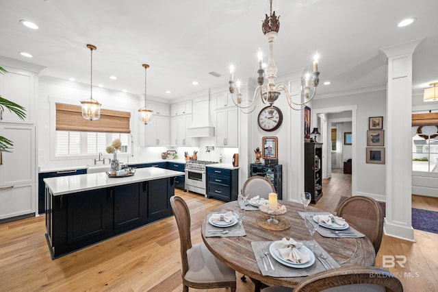 dining space featuring ornate columns, plenty of natural light, ornamental molding, and light wood-type flooring