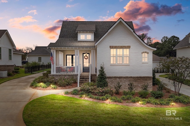 view of front of home featuring covered porch, a yard, and central AC unit