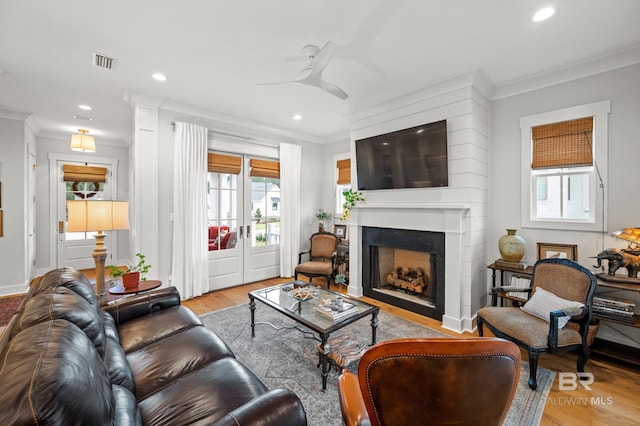 living room with light hardwood / wood-style floors, ceiling fan, and crown molding