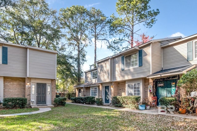 townhome / multi-family property with a front lawn and brick siding