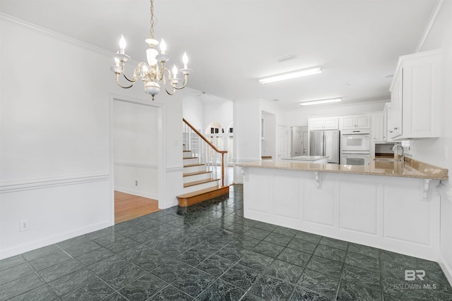 kitchen with double oven, sink, white cabinets, stainless steel fridge, and kitchen peninsula