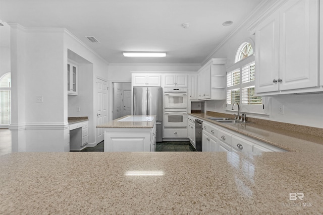 kitchen featuring sink, ornamental molding, appliances with stainless steel finishes, a kitchen island, and white cabinets