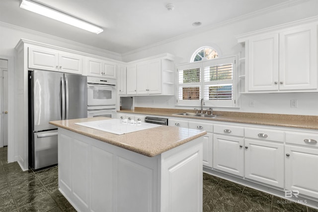 kitchen featuring sink, a kitchen island, white cabinets, and appliances with stainless steel finishes