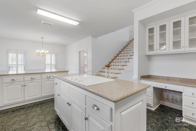 kitchen with white cabinetry, built in desk, a kitchen island, decorative light fixtures, and white electric stovetop