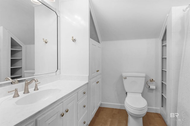 bathroom featuring vanity, hardwood / wood-style floors, lofted ceiling, and toilet