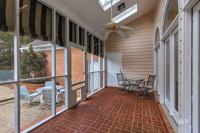 unfurnished sunroom featuring ceiling fan and vaulted ceiling with skylight