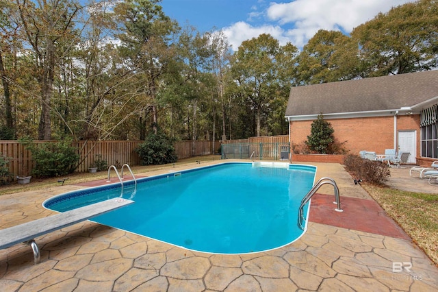 view of pool with a diving board and a patio area