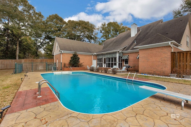 view of swimming pool with a diving board and a patio