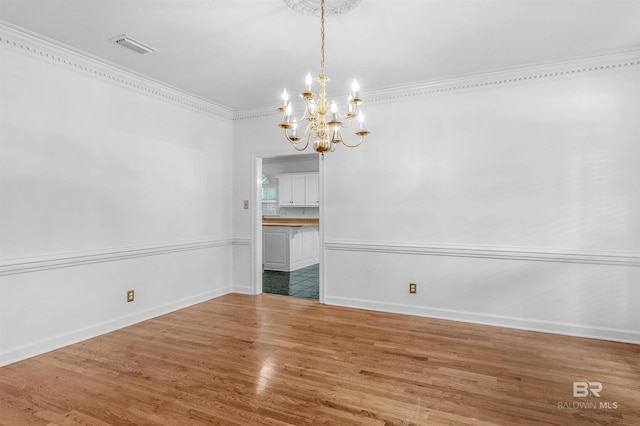 unfurnished dining area with crown molding, a notable chandelier, and hardwood / wood-style flooring