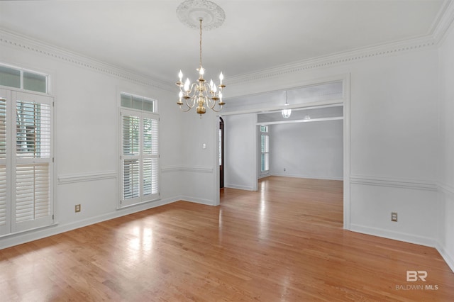 empty room with ornamental molding, a chandelier, and light hardwood / wood-style flooring