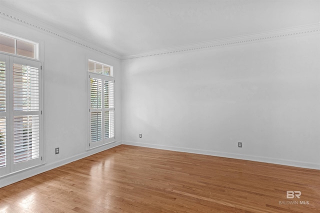 empty room with crown molding and light hardwood / wood-style floors