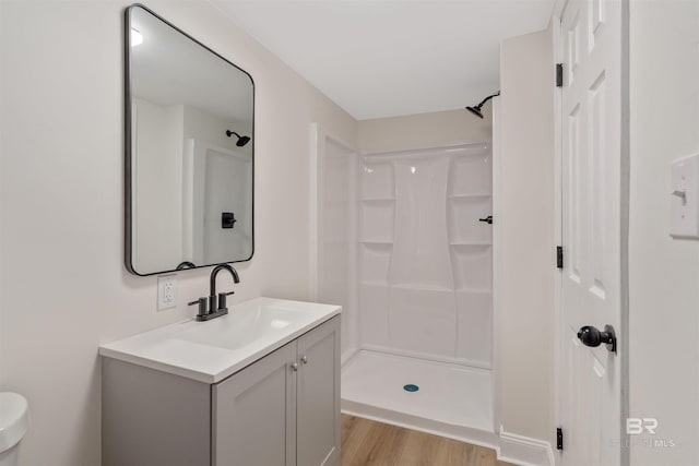 bathroom featuring vanity, hardwood / wood-style flooring, toilet, and walk in shower