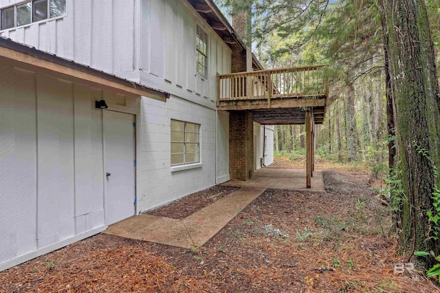 view of property exterior featuring a wooden deck and a patio