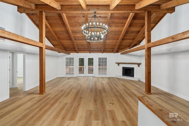 unfurnished living room featuring beamed ceiling, light hardwood / wood-style floors, an inviting chandelier, and wood ceiling