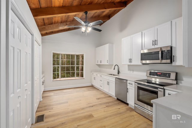 kitchen featuring white cabinetry, sink, appliances with stainless steel finishes, and vaulted ceiling with beams