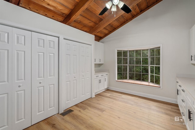 unfurnished bedroom with wood ceiling, two closets, ceiling fan, light hardwood / wood-style flooring, and vaulted ceiling with beams