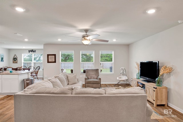 living room featuring light wood-type flooring, ceiling fan, and plenty of natural light