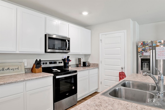 kitchen featuring white cabinetry, wood-type flooring, stainless steel appliances, and sink