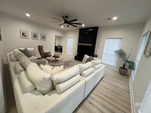 living room with a large fireplace, ceiling fan, and light hardwood / wood-style flooring