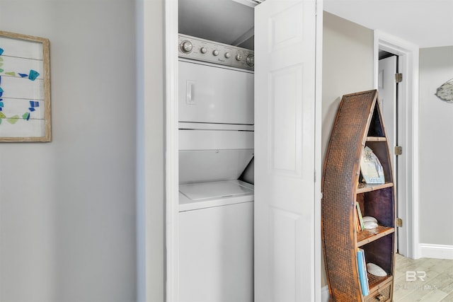 laundry room featuring stacked washer / dryer and light hardwood / wood-style flooring