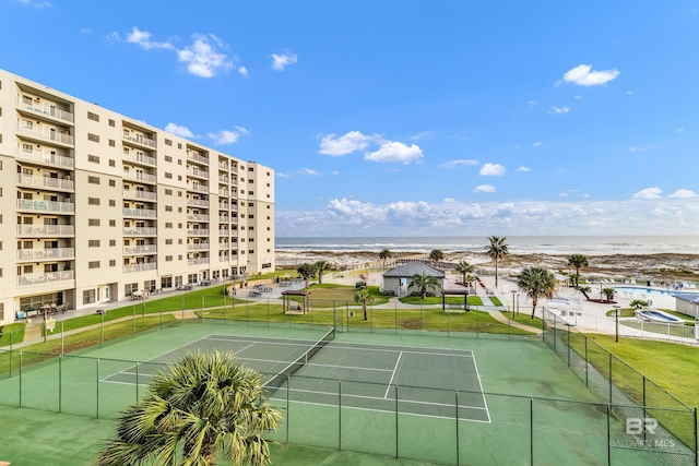 view of tennis court featuring a water view and a beach view