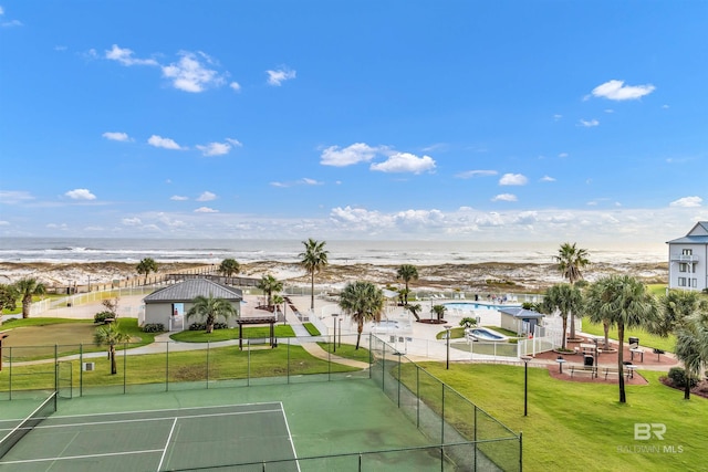 view of sport court with a beach view, a water view, and a yard