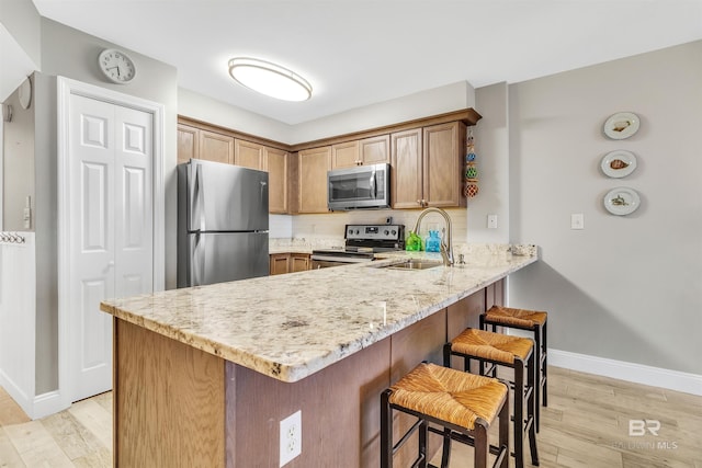 kitchen featuring stainless steel appliances, light hardwood / wood-style floors, sink, and kitchen peninsula