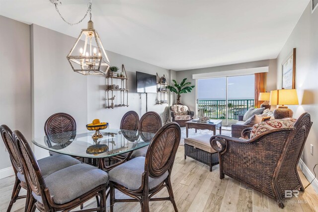 dining space with light wood-type flooring and a notable chandelier