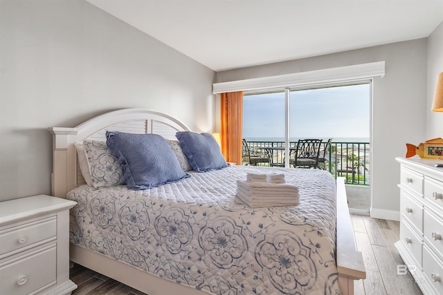 bedroom with hardwood / wood-style flooring, access to exterior, and a water view