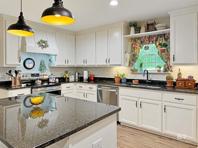 kitchen with hanging light fixtures, stainless steel appliances, dark stone countertops, sink, and white cabinetry