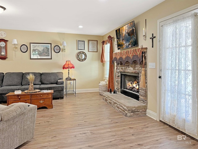 living room featuring a stone fireplace and light wood-type flooring