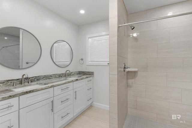 bathroom with double vanity, a sink, and tiled shower