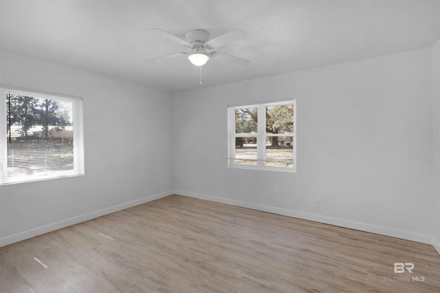 unfurnished room featuring light wood-type flooring, a wealth of natural light, and baseboards