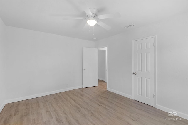 spare room with light wood-style floors, visible vents, ceiling fan, and baseboards