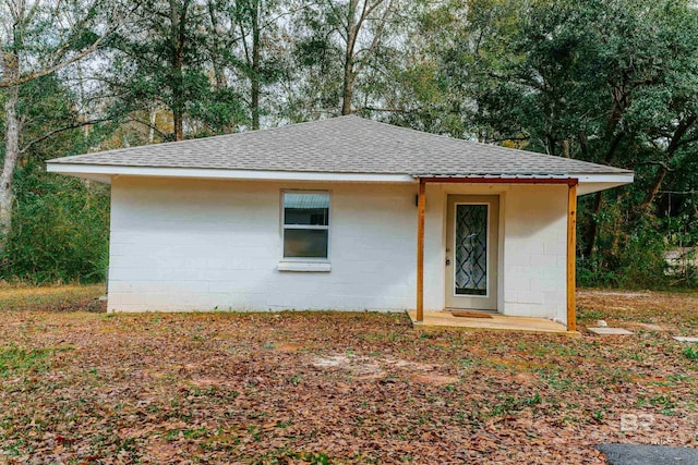 exterior space with a shingled roof and concrete block siding