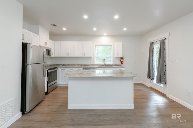 kitchen featuring appliances with stainless steel finishes, a center island, visible vents, and white cabinetry